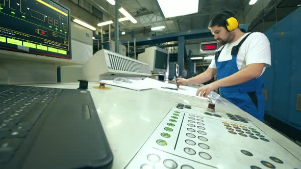 Engineer, Worker at a Factory Facility. Operation Board and a Male Worker Taking Notes Near It alt