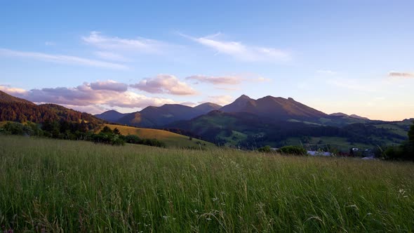 Green Grassy Meadow and Beautiful Mountain Panorama in the Morning Light Golden Hour