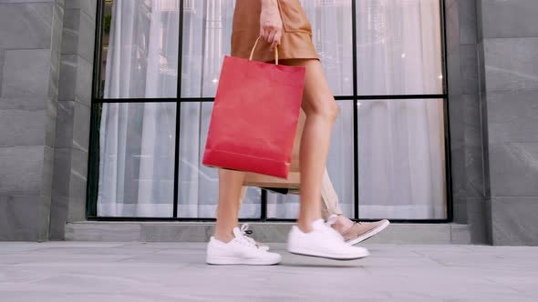 Shot of legs' man and woman holding a shopping bag in the street and walking together, relationship