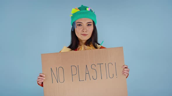 Woman holding cardboard with inscription no plastic on it.