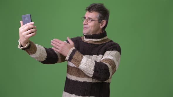 Mature Handsome Man Wearing Turtleneck Sweater Against Green Background