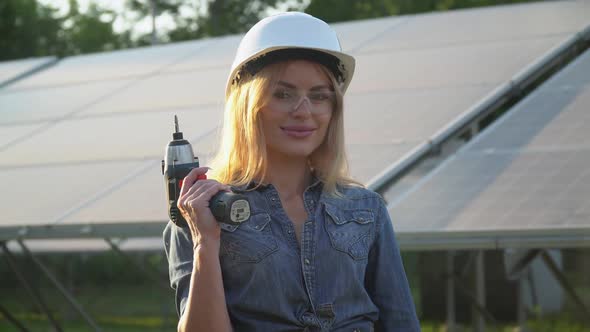 Female Engineer in a White Helmet with Screwdriver Is at the Solar Power Station, Alternative Energy alt