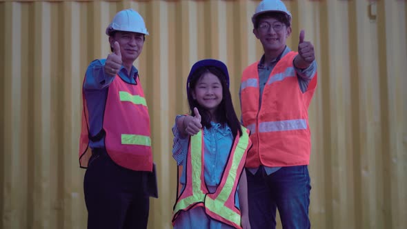 Happy family standing with showing thumbs up at container cargo site