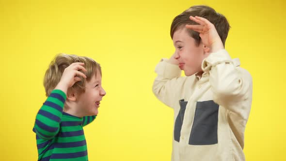 Side View Portrait of Playful Carefree Caucasian Brothers or Friends Making Faces with Tongue Out at alt