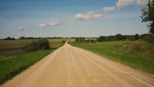 Yellow gravel road through the fields of Latvia