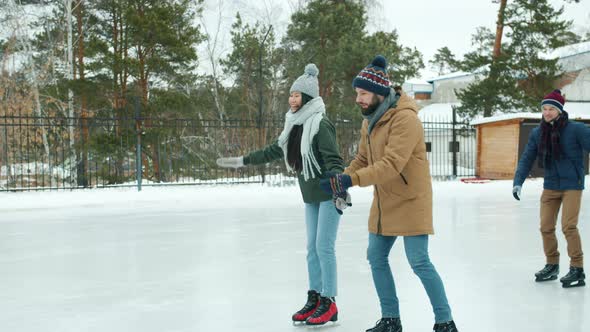Happy Couples Ice-skating in Park Holding Hands Laughing Having Fun Together alt