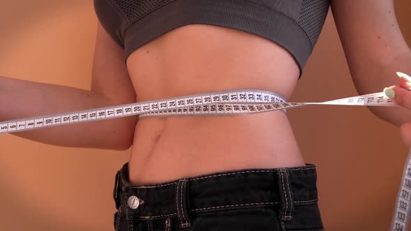 Girl with a Beautiful Figure Put On Old Big Jeans and Measures Her Waist alt