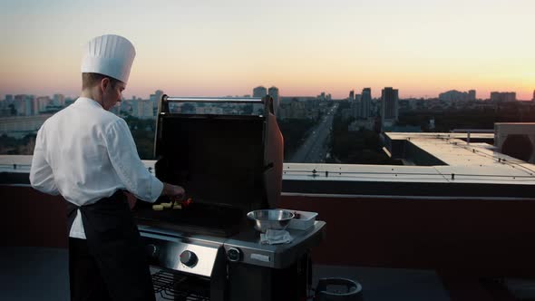 A professional Chef prepares a barbecue on the rooftop of a skyscraper. An expensive restaurant alt