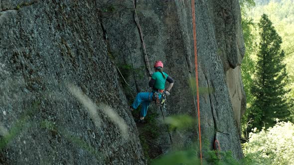 A Young Woman Descends From the Cliff on a Rope