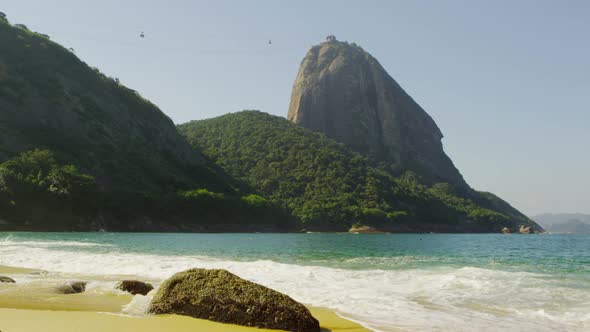 Slow motion shot of the beautiful Red Beach in Rio with waves washing over exposed boulders. alt