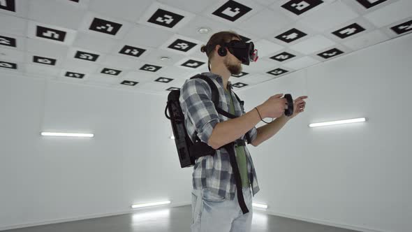 Young Man in Virtual Reality Headset Is Spending Time in Augmented Reality in an Empty Playroom Full