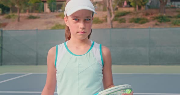 Young Tennis Player Looks Into the Camera While Holding Her Colorful Racket alt