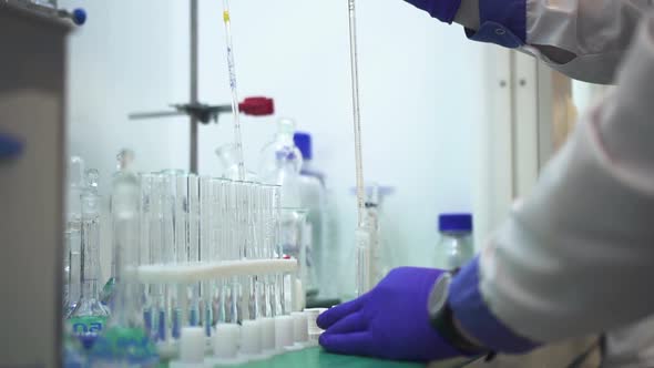 Scientist Hand Drips Liquid in a Pipette with Measured Numbers Into Test Tubes Spbd alt