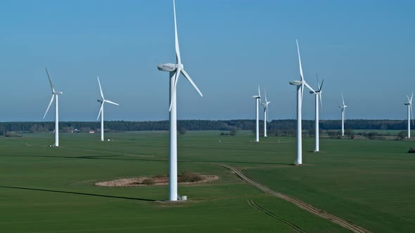 Large wind turbines with blades in field aerial view blue sky.