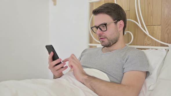 Beard Young Man Using Smartphone in Bed alt