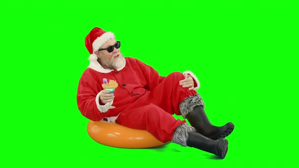 Santa claus sitting on inflatable tube and having cocktail alt