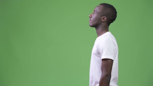 Profile View of Young African Man Against Green Background alt