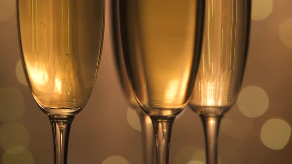 Champagne glasses over holiday bokeh blinking background, rotating on turntable