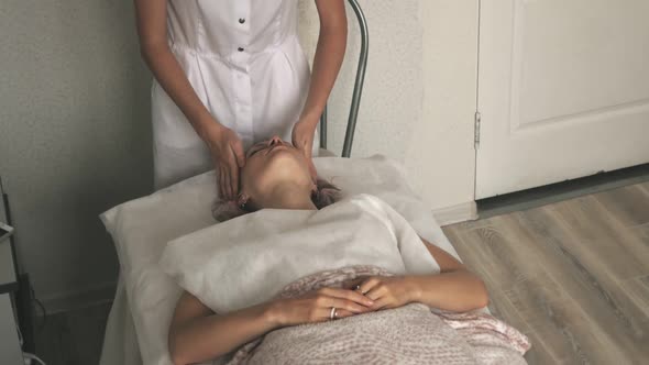 A Masseur Gives a Woman a Professional Facial Massage