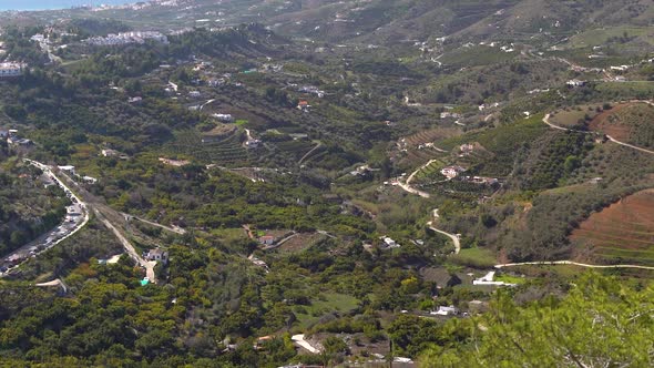Slow cinematic tilt up over beautiful green countryside with scattered houses and ocean alt
