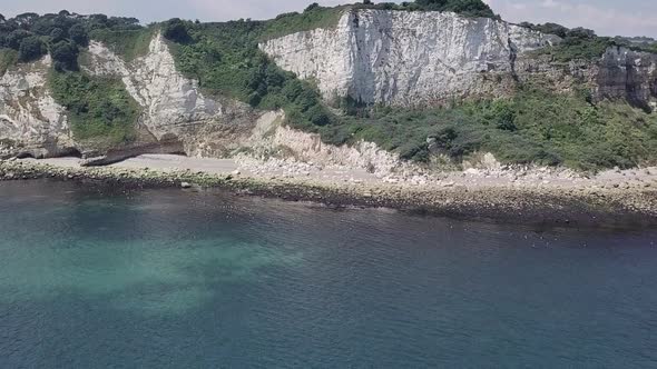 Flying towards the cliffs of Seaton beach in England. Rock formation and boulders are visible on the alt