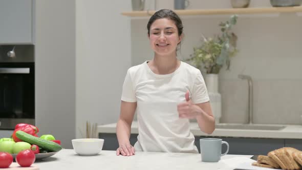 Indian Woman Showing Thumbs Up While Standing in Kitchen alt
