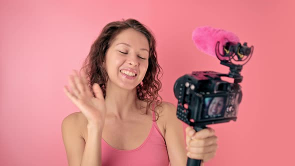 Young Woman Vlogger Recording Broadcast in Slow Motion on a Pink Background alt