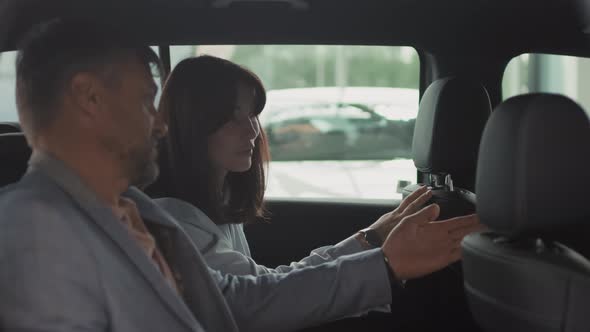 Man and Woman Inspecting Car Interior in Dealership alt