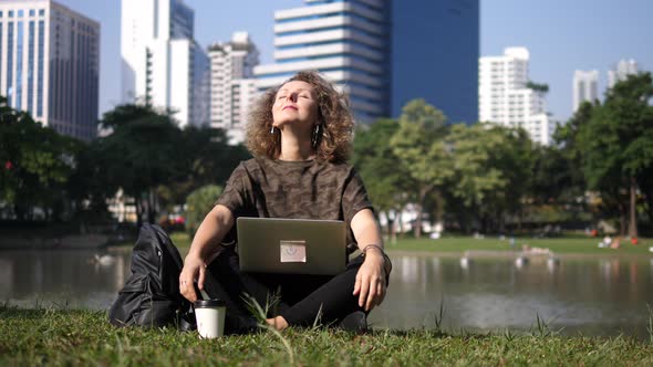 Happy Woman Working On Laptop Enjoying Sunshine In Park alt