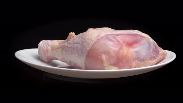 chicken leg or thigh with shin lies on white plate and rotates on turntable alt