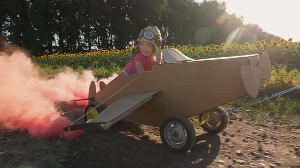Happy Little Girl Driving a Cardboard Plane alt