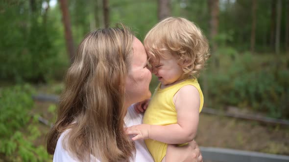 Little Cute Baby Toddler Girl Blonde with Curls on Mother's Arms alt