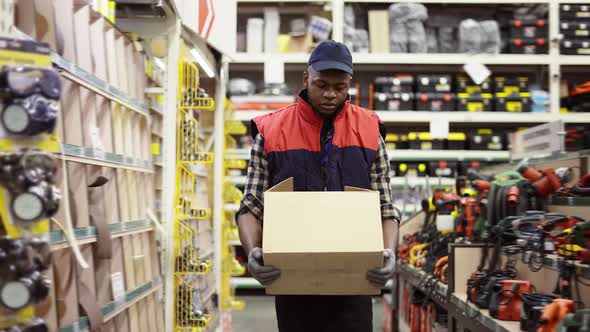 Worker in Hardware Store Carrying Box alt