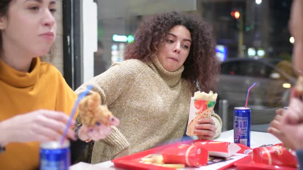 young women multiethnic indoor eating at fast food alt