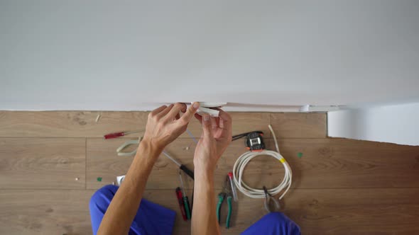 An Electrician Installs an Electric Socket Outlet Into Wall alt
