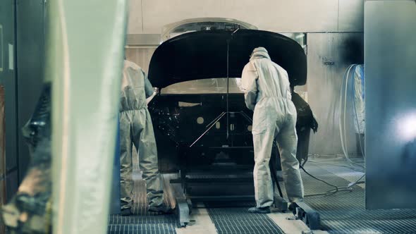 Factory Workers Spray Painting a Car Body at a Car Production Factory alt