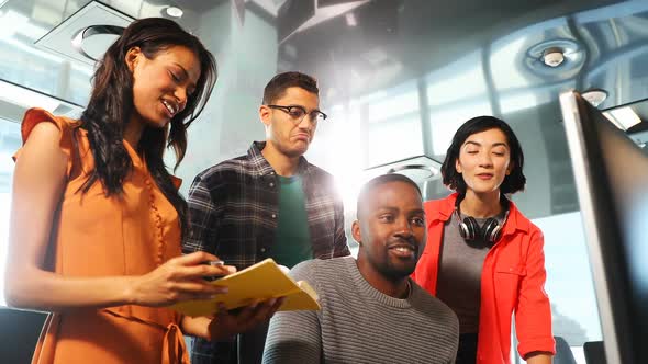 Business colleagues discussing over computer 4k alt