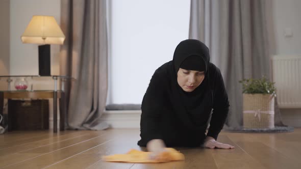 Portrait of Beautiful Muslim Woman in Hijab Cleaning the Floor and Wiping Forehead with Hand alt
