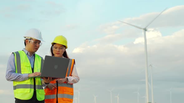 engineer team working with laptop computer against wind turbine farm