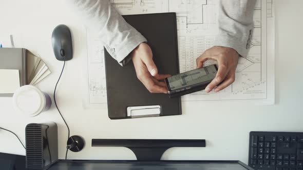 Desktop Civil Engineer Hands Men Work with Drawings on Mobile Phone and Paper alt