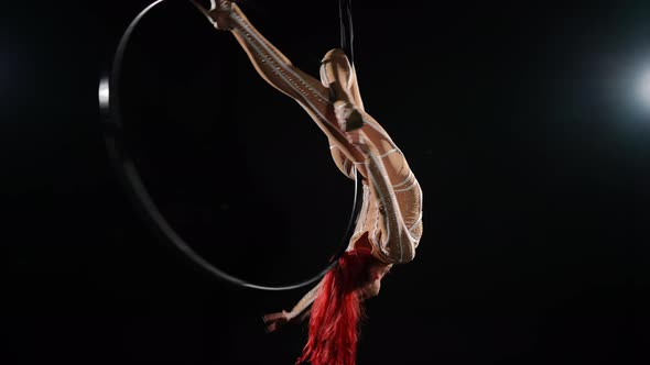 Redhead Slim Seductive Woman Hanging Upside Down on Air Hoop Spinning Looking at Camera Smiling alt