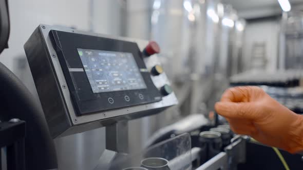 Worker's Hand In Rubber Glove Pressing On Automated Machine In A Beer Factory alt