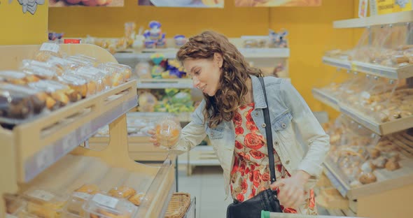 Pretty Young Woman Chooses Bakery in the Bread Department of the Supermarket alt