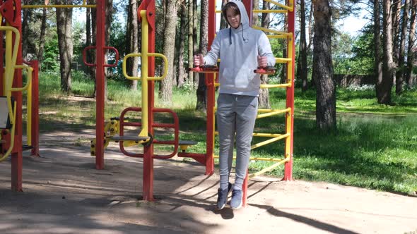 Single Young Man Doing Exercises at Street Gym Apparatus in Park Street Workout