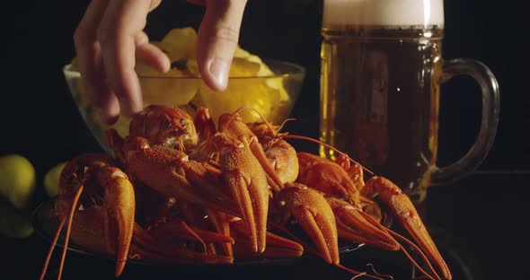 Close Up View of Man Arm Taking Lobsters with Foamy Bear Pouring in Glass and Crisp Chips on