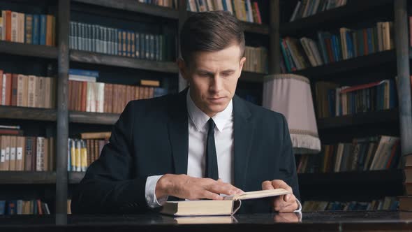 Businessman in Classical Suit Sitting in Library Reading Book