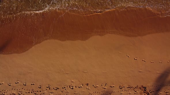 Waves rolling ashore. Woman walks on the beach. Top view (aerial), background. alt