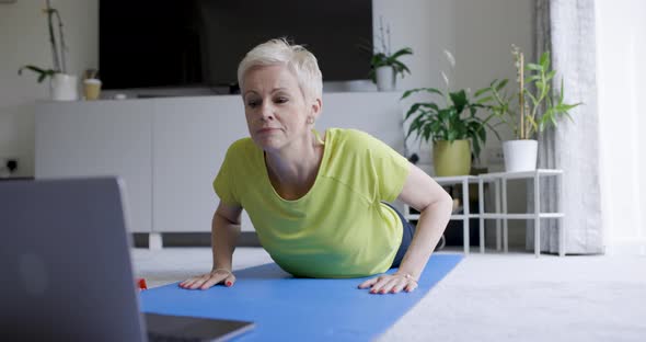 Mature woman practicing online yoga with laptop