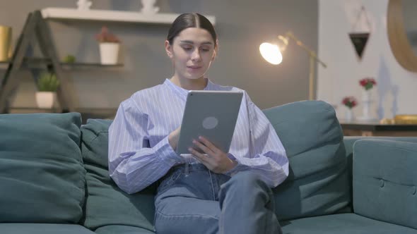 Hispanic Woman using Tablet While Sitting on Sofa alt