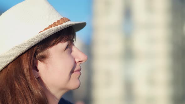 Profile of a Happy Woman in a Hat on the Street Looking at the Sky and Smiling
